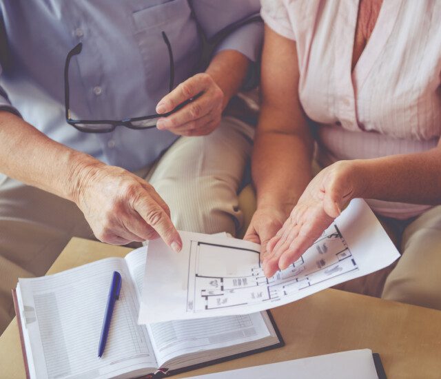 close-up of seated couple looking at printed floor plans together