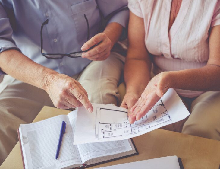 close-up of seated couple looking at printed floor plans together