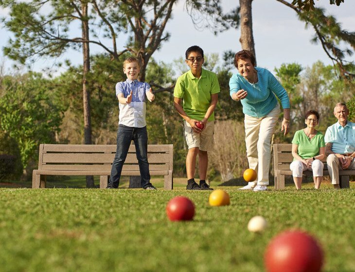 Resident at Village on the Green playing bocce balls with grandchildren.