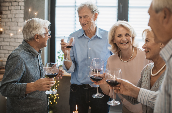 A group of seniors celebrating with wine and snacks